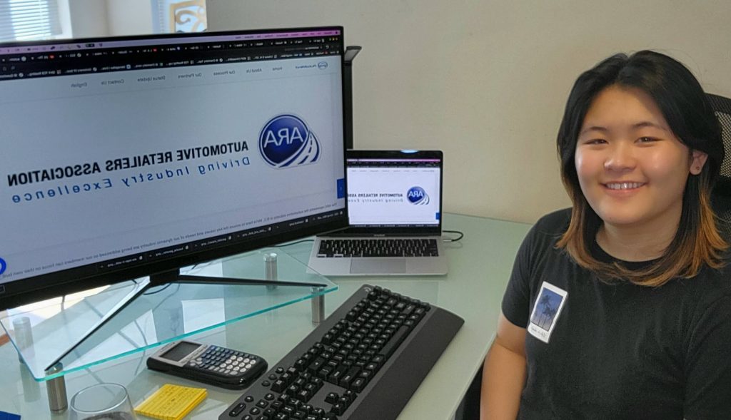 Nicole Ting, a BEST co-op student, sitting at her desk with her laptop and smiling while on the company's website.