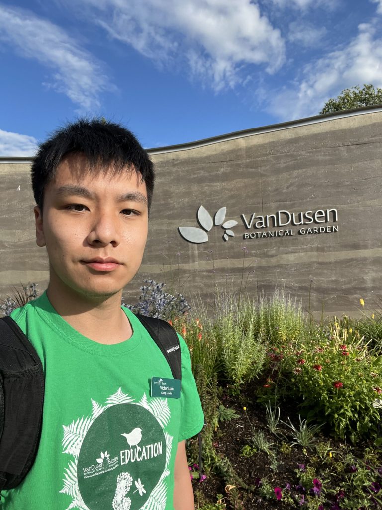Victor standing in front of VanDusen sign and smiling.