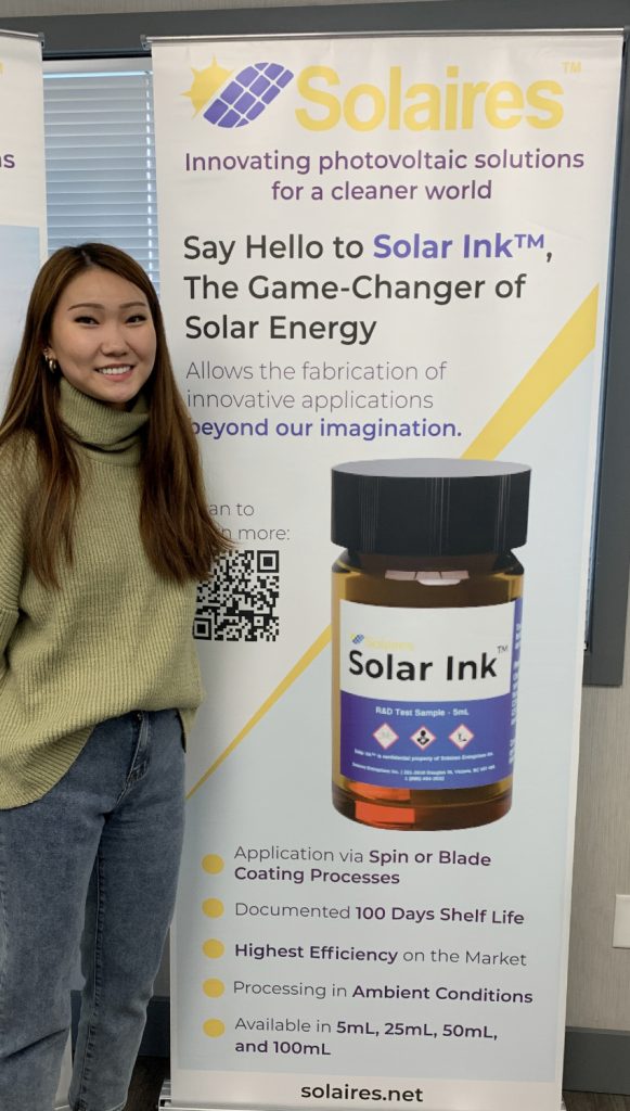 En Jung Hwang standing in front of a poster for Solaires and smiling.