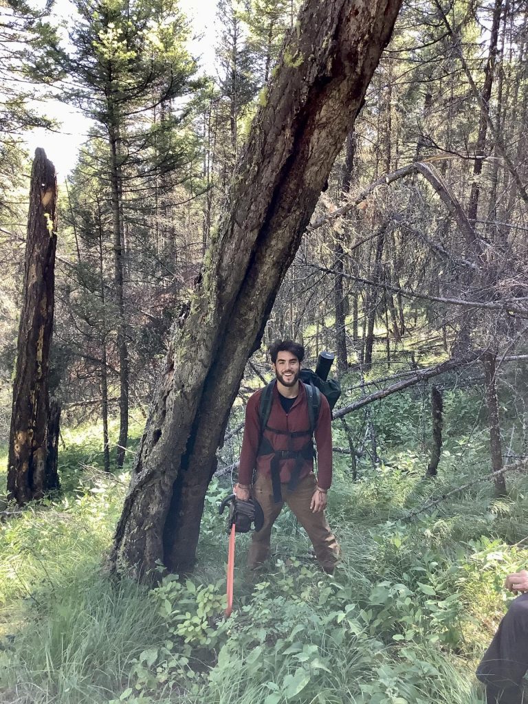 Ethan standing in a forest and smiling.