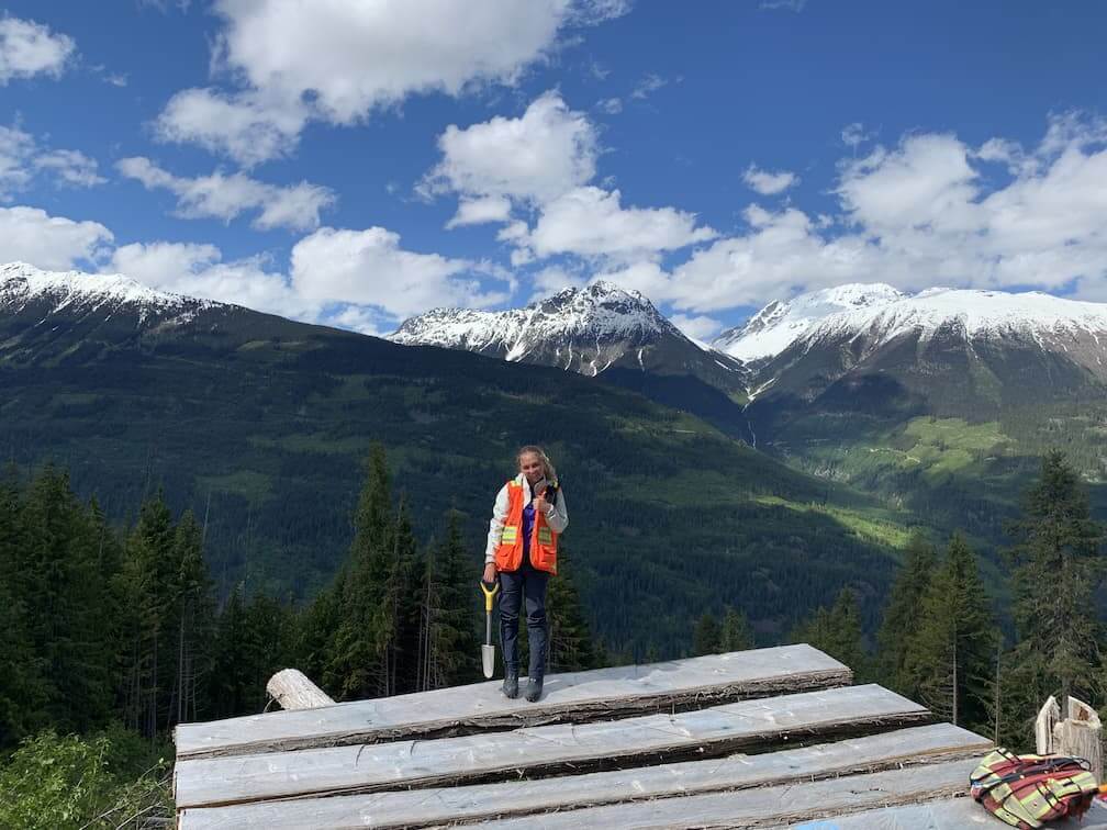 Alexandra Hankins, a UBC Forestry Co-op Student, is standing on a platform wearing safety attire and smiling. 