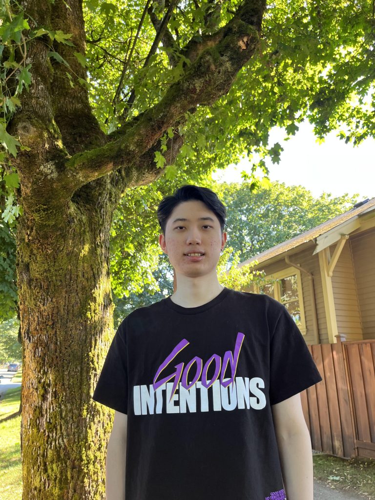 Xin standing in front of a tree and smiling.