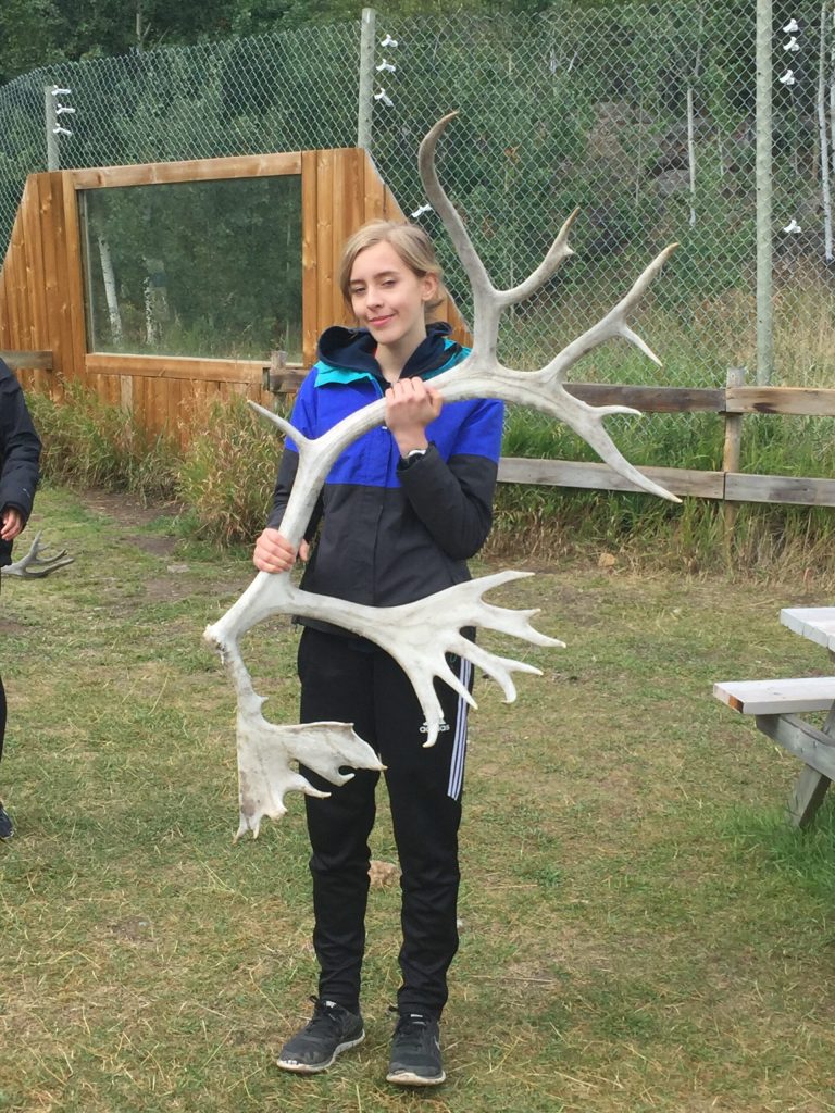 Olivia holding deer antlers and smiling.
