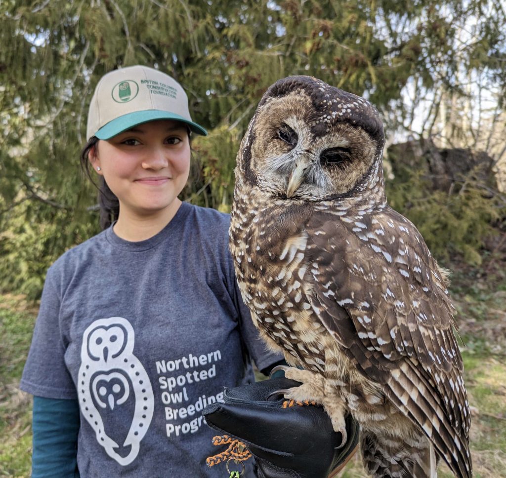 Kayleah holding a spotted owl and smiling.