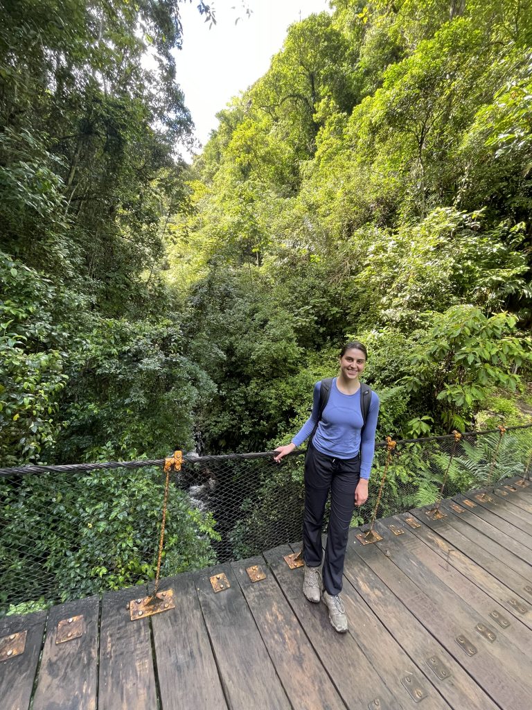 Belen standing on a suspension bridge and smiling.